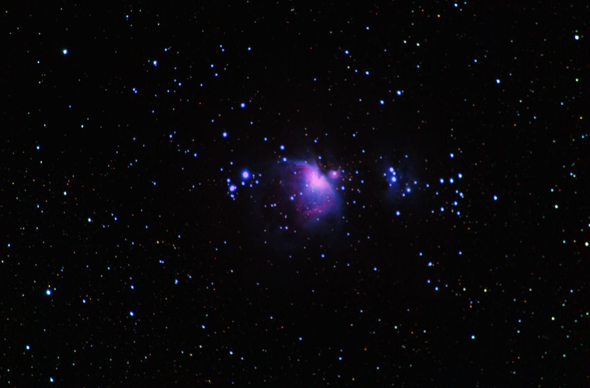 ओरायन नीहारिका (M42) ट्रैपेज़ियम के चारों ओर गुलाबी चमकती हुई, ऊपरी दाईं ओर नीली रनिंग मैन नीहारिका (NGC 1977) के साथ