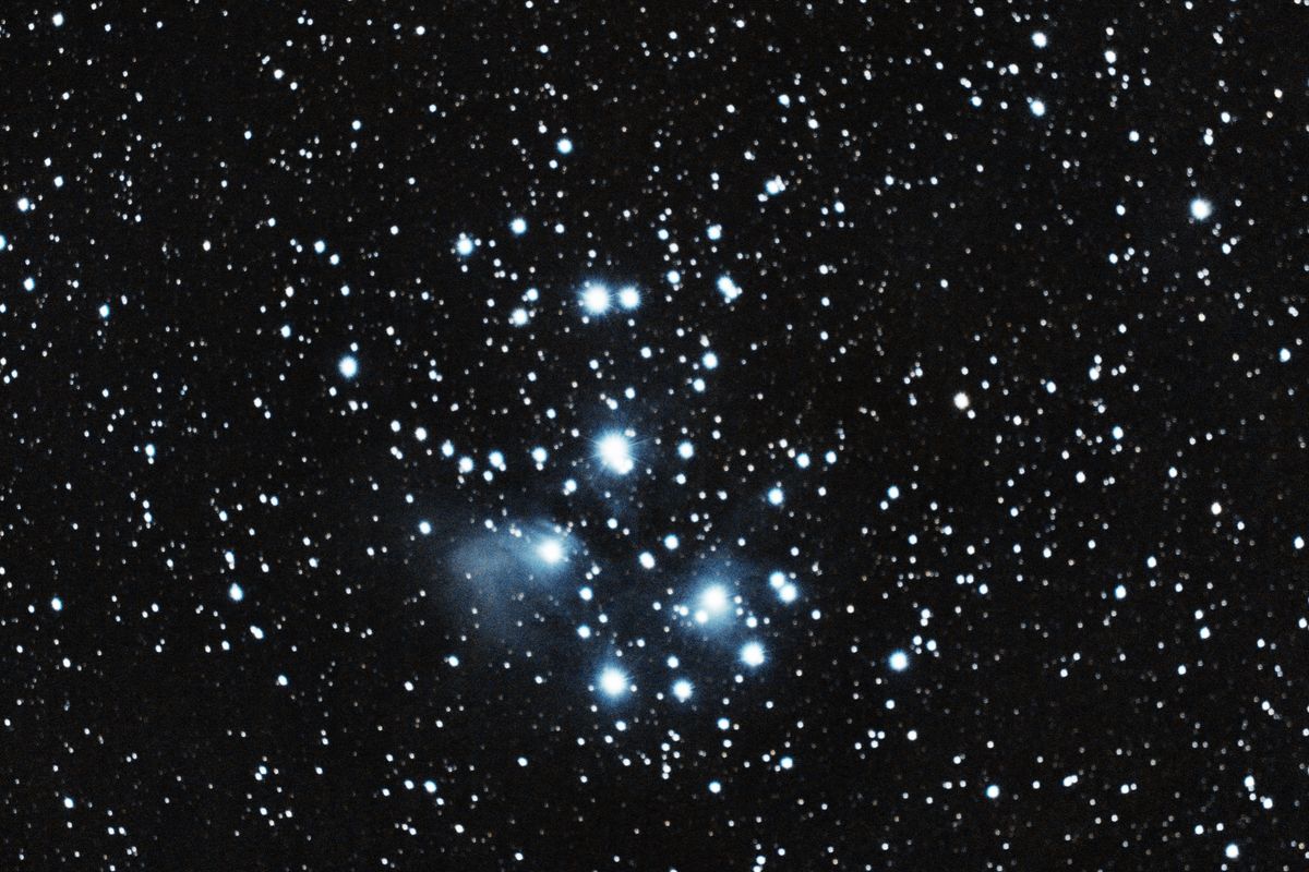 कृत्तिका खुला तारागुच्छ (M45) — चमकीले नीले तारे धुँधली नीली परावर्तन नीहारिका में लिपटे हुए